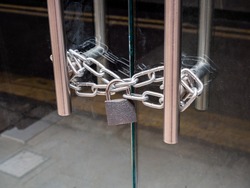 London, UK. May 14th 2020: A retail shop glass front doors, padlocked and chained shut. For security and safety. London lockdown, coronavirus, cover-19 outbreak.