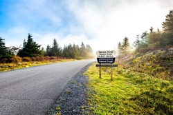 Spruce Knob West Virginia mist fog autumn fall season and sign on empty road in morning for highest point in Monongahela national forest Appalachian Allegheny mountains
