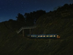 View of train moving under bridge  in mountain area on starry night