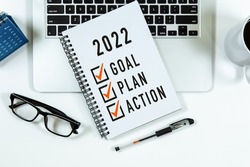 2022 Goal, Plan, Action checklist text on note pad with laptop, glasses and pen.