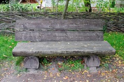 Weathered Ancient Wooden bench Along Trail in park in woodOld wooden bench surrounded in a forest surrounded by autumn leaves