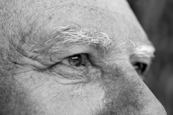Closeup eye of caucasian old man. Portrait of old man outdoors. Caucasian male face background, close up eyes, macro, black and white
