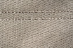 Thread stitching on light denim. Beige jeans fabric background or denim texture. Close up view