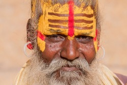 Hindu sadhu holy man, sits on the ghat, seeks alms on the street in Jaisalmer, Rajasthan, India . Close up