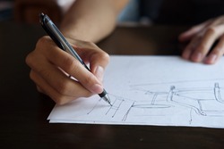 Hand of Designer with a pen, designing and sketching his idea