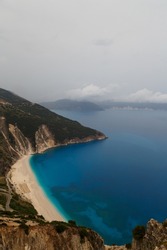 Top view at Myrtos Beach from road during bad weather conditions, thunderstorm and rain, with low dark clouds over sea. Cephalonia, Greece.