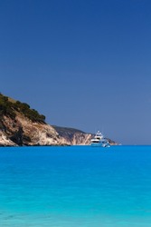 White yacht anchored in fantastic Myrtos Beach turquoise and blue bay. Summer scenery of famous and extremely popular travel destination in Cephalonia island, Greece, Europe