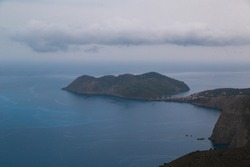Top view at Asos village and Assos peninsula during bad weather conditions, thunderstorm and rain, with low dark clouds and visible currents at sea. Cephalonia, Greece