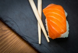 Sushi and Sashimi rolls on a black stone slatter. Fresh made Sushi set with salmon, prawns, wasabi and ginger. Traditional Japanese cuisine.