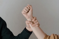 Domestic violence.
Man's hand grabbing a woman's arm.
Concept of gender violence and mistreatment of women.
Background isolated on gray background