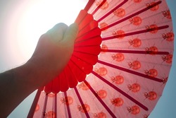 Hand fan Red.Heat wave shoots thermometers with extreme temperatures. Hand fan covering the sun to cool down and give yourself air in heat alerts. Heat wave  heatstroke concept. 