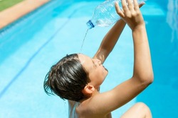 Heatstroke.heatwave. Cool off in the summer heat wave in the pool. young man splashing a bottle of water on his face. Concept of high temperatures in summer.heatstroke
