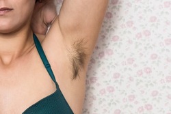 Hairy woman's armpit. Woman without waxing. Unplucked hair. Woman showing unshaven natural body hair. Hair growing in the armpit with unshaven lumps. self-confident girl. Hair woman concept. hairy fem