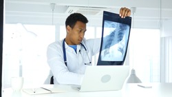 Afro-American Doctor Examing X-ray of Patient, Lungs and Ribcage