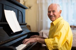 Elderly composer composes music and plays piano