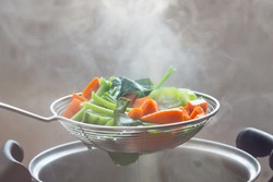 The steam from the vegetable colander in the darkSelective focus.