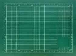 Old green color cutting mat with grid and scale.