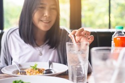 Happy asian woman drinking water during meal at restaurant