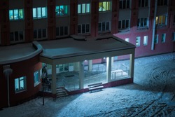 Entrance to the hospital overnight. Veranda clinic in the winter. People on the porch under the lantern. Building's facade.
