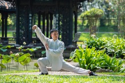Asian man working out with Tai Chi in the morning at the park, Chinese martial arts, healthy care for life concept.