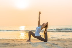 Young healthy Yoga woman workout yoga pose on the beach at sunrise, benefits of natural environments for physical, spiritual, healthy, relaxing concept. 
