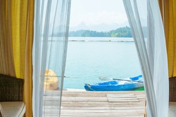 Bedroom view with kayak on a lake and mountain with window curtains.