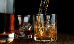 Detail of pouring whiskey into glass on black background
