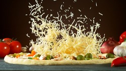 Falling mozzarella cheese on pizza, freeze motion. Italian traditional meal.
