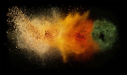 Freeze motion of various spice explosion, abstract culinary background. Isolated on black background