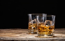 Whiskey drinks on wood with ice cubes