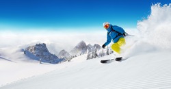 Skier on piste running downhill in beautiful Alpine landscape. Blue sky on background. Free space for text