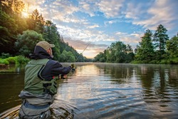 Sport fisherman hunting predator fish. Outdoor fishing in river during sunrise. Hunting and hobby sport.
