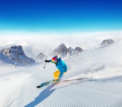Young man skier running down the slope in Alpine mountains. Winter sport and recreation, leisure outdoor activities.