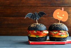 Halloween Spooky Black  Burger. Cheeseburger on Halloween pumpkin head jack lantern holiday food background	