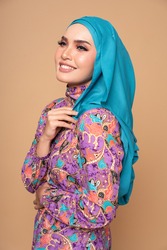 Beautiful female model wearing modern batik kebaya with hijab, an Asian traditional dress for Muslim woman isolated over beige background. Stylish Muslim female fashion lifestyle  concept.