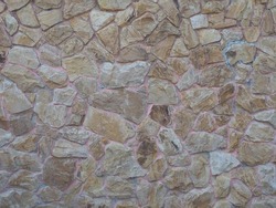 Wall with beige randomly laid out stonework. Non-seamless texture. Full screen photo