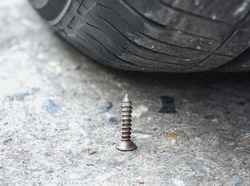 Sharpen metal screw nail nearly to puncture into wheel tire, selective focus (colored filter effect)