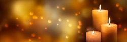 three candle lights at the edge of blurred festive background, decorative golden shiny candle lights