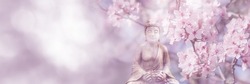 flowering cherry tree around buddha statue on sunny blurred spring background, idyllic nature scene in sunhine, web banner concept with copy space