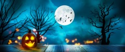 halloween background with full moon and lantern on wooden space at blue night, defocused lights on blurred cloudy sky, concept with advertising space