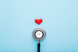 Stethoscope with red heart on light blue table background. Pastel color. Doctor tool for heartbeat listening. Healthcare concept. Closeup.
