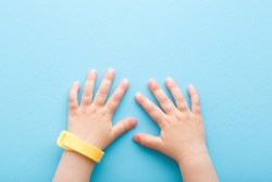Yellow mosquito repellent band on baby wrist on light blue table background. Pastel color. Closeup. Point of view shot. Protection from insects.