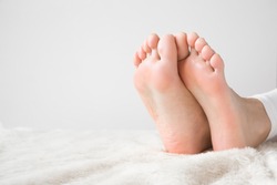 Elegant bare feet. Beautiful groomed woman's feet on the fluffy blanket. Cares about clean and soft legs skin. Lying and enjoying rest.