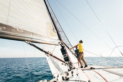 Beautiful inspiring shot of action adventure of sailor or captain on yacht or sailboat attaching big mainsail or spinnaker with ropes on deck of epic boat, sunny summer adventure lifestyle