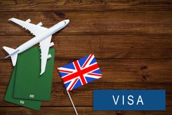 V Britain concept. Text  near passport cover and british flag on wood background top view
