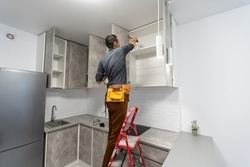 Caucasian repair master electrician man standing in apartment at stepladder