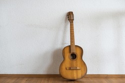 classic guitar lying in front of a wall as background