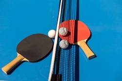 Table tennis rackets and a white plastic ball on a blue background.