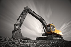 Excavator parked on stone ground against dramatic sky