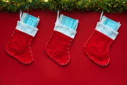 Horizontal color image with an overhead view of a christmas decoration with Coronavirus on a red background, christmas socks, face masks and hydroalcoholic gels. Covid concept on christmas.